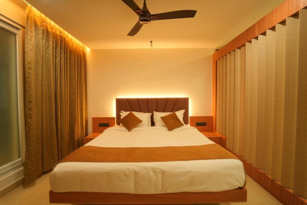 Una habitación de hotel con una cama grande, un ventilador de techo y cortinas.