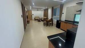 A modern kitchen with a black countertop, wooden cabinets, and a built-in dishwasher. - Arunaragha (Mysore)
