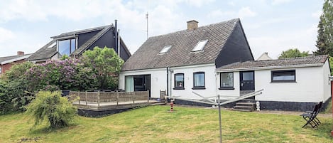 A two-story house with a sloped roof, a front porch, and a small garden.