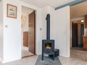 A room with a black wood-burning stove, a framed picture on the wall, and a wooden door leading to another room.