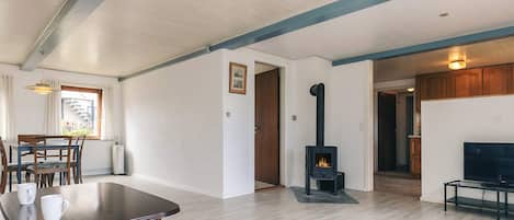 A spacious living area with a fireplace, a dining table with chairs, and a television on a stand.