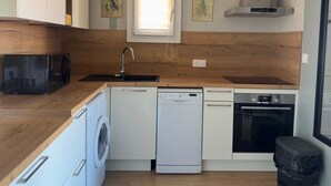 Een kleine keuken, voorzien van een wasmachine, vaatwasser, magnetron en oven.
