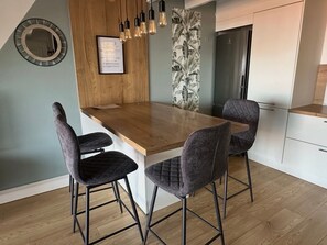 A modern kitchen with a wooden island, two bar stools, pendant lighting, a refrigerator, and a framed quote on the wall. - Comfortable apartment with AC - 4 guests (Collioure)