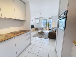 Un appartement moderne comprenant une cuisine, un salon et un coin repas, et offrant une grande fenêtre avec vue sur la ville.