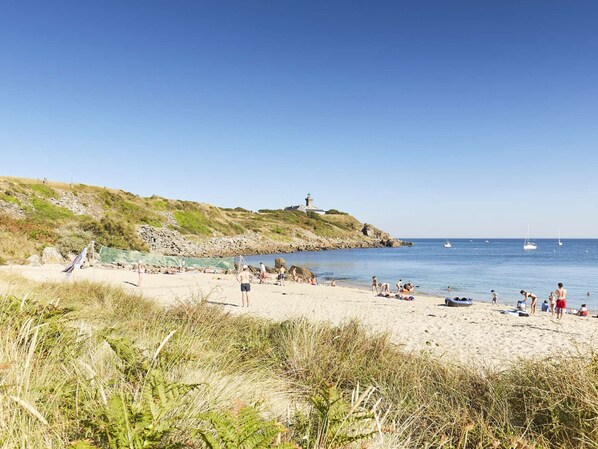 Ein Strand mit Menschen, einem Leuchtturm und Booten.