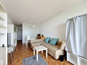 Ein modernes Wohnzimmer mit Sofa, einem kleinen Tisch, einem Fernseher und einem Essbereich.