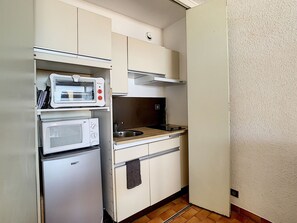 Eine kleine Küche mit Mikrowelle, Backofen und Spüle.