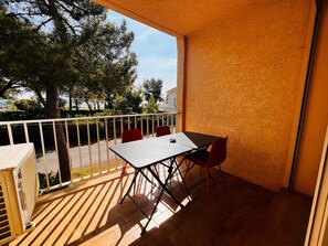 A balcony with a table and chairs, a small heater, and a view of trees and buildings. - Apartment, AC, sea view - 4 guests (Argelès-sur-Mer)
