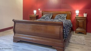 A bedroom with a wooden bed, two bedside tables with lamps, a red wall, and a wooden floor. - Charming house in the heart of Perche - 4 guests (Longny-au-Perche)