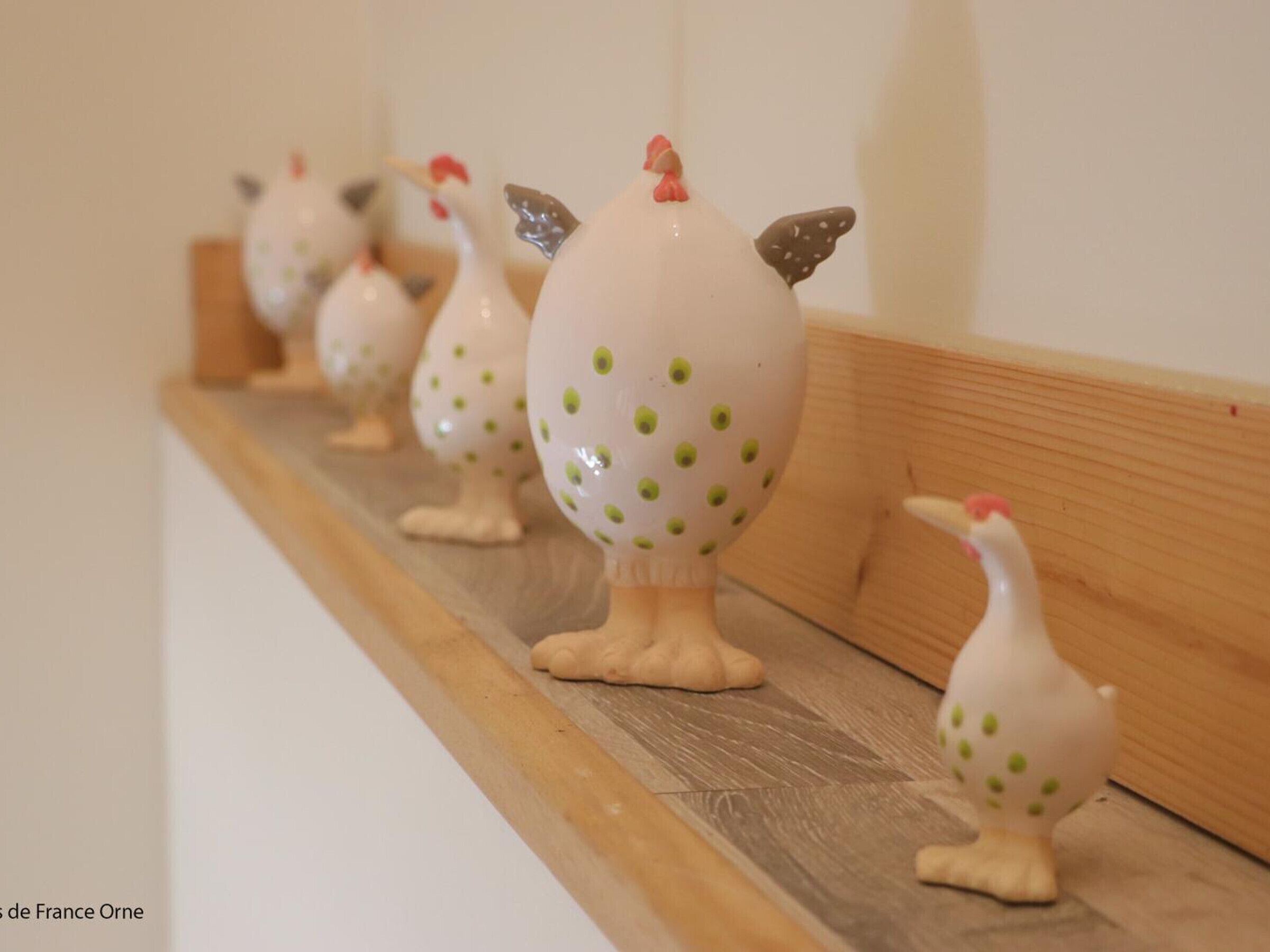 Ceramic chicken figurines on a wooden shelf.