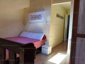 A bedroom with a bed, bedside table, and a door leading to another room. - Duplex with lake view - 4 guests (Les Angles)