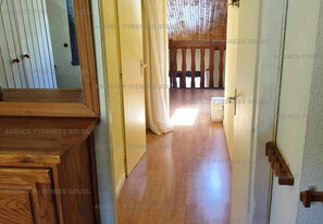 A hallway with wooden flooring, a door leading to a room with a wooden ceiling, and a view of a balcony. - Duplex with lake view - 4 guests (Les Angles)