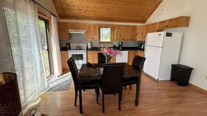A kitchen with wooden cabinets, a white refrigerator, and a dining table with chairs.