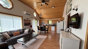A spacious living area with a sofa, coffee table, and a television mounted on the wall.