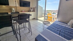 Une chambre moderne équipée d’un lit, d’une table à manger avec des chaises, d’une machine à café et d’une grande fenêtre.