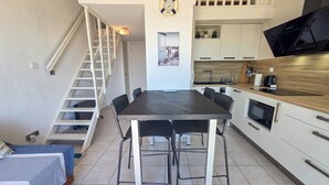 Une cuisine compacte comprenant une table à manger, des chaises, un four à micro-ondes et un escalier.