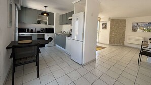 Una cocina moderna con lavadora, un comedor con mesa y sillas, y una pared de acento de piedra.