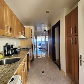 A kitchen with wooden cabinets, a granite countertop, a coffee maker, and a refrigerator.