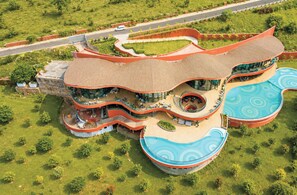 A modern hotel with a unique curved architecture, a central swimming pool, and a landscaped garden.