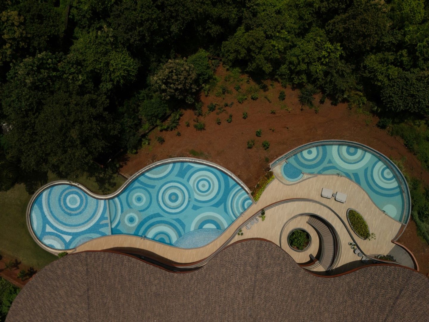 An aerial view of a unique building with a circular swimming pool and a spiral staircase.