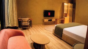 A hotel room with a bed, a desk, a chair, a television, and a sofa. - Tomorrow Land by Miros - Anjarle (Dapoli)