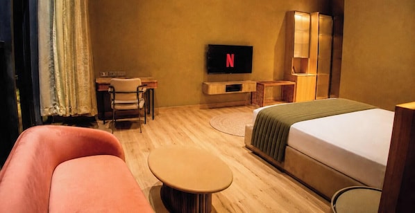 Habitació d'hotel amb llit, escriptori, cadira, televisió i sofà.