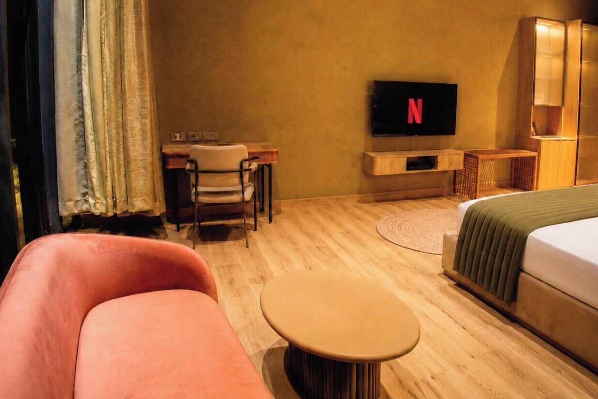 Una habitación de hotel con una cama, un escritorio con una silla, un televisor y una pequeña mesa redonda.