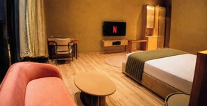 Une chambre d’hôtel comprenant un lit, un bureau avec une chaise, une télévision et une petite table ronde.