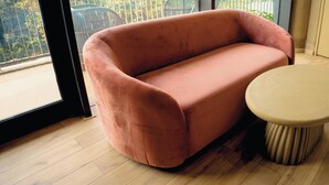 A room with a pink sofa, a round table, and a view through a window. - Tomorrow Land by Miros - Anjarle (Dapoli)