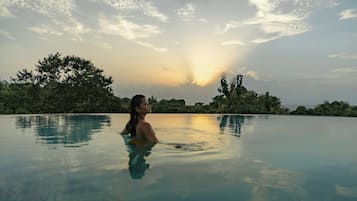 Une personne dans une piscine, avec un coucher de soleil en arrière-plan.