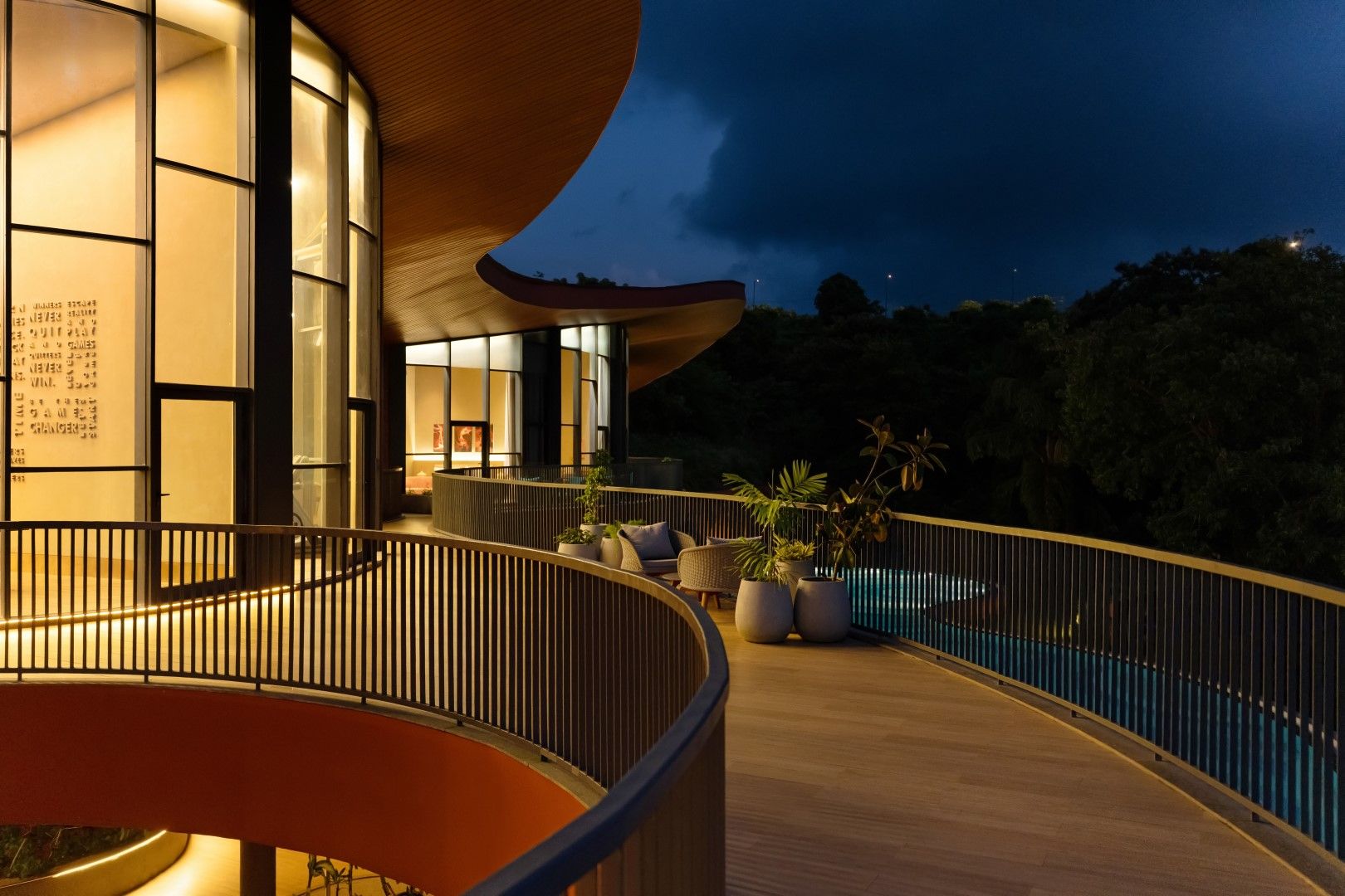 A modern building with a curved balcony overlooking a pool.