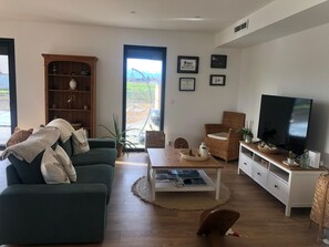 Ein Wohnzimmer mit einer Couch, einem Fernseher, einem Bücherregal und einem Esstisch.
