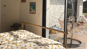 A bedroom with a bed, a hanging basket, and a view of the outside. - New house with swimming pool 10 minutes from Pau, ideal for relaxing and enjoying. (Bordes)