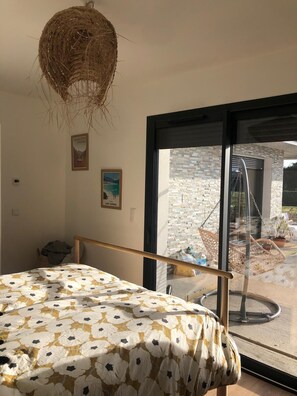 Ein Schlafzimmer mit Bett, einer Hängekorb und Blick ins Freie.