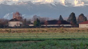 A rural landscape with a field, buildings, and snow-capped mountains in the background. - New house with swimming pool 10 minutes from Pau, ideal for relaxing and enjoying. (Bordes)