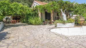 Un cortile in pietra con un edificio caratterizzato da un tetto in tegole, circondato da piante e vasi.