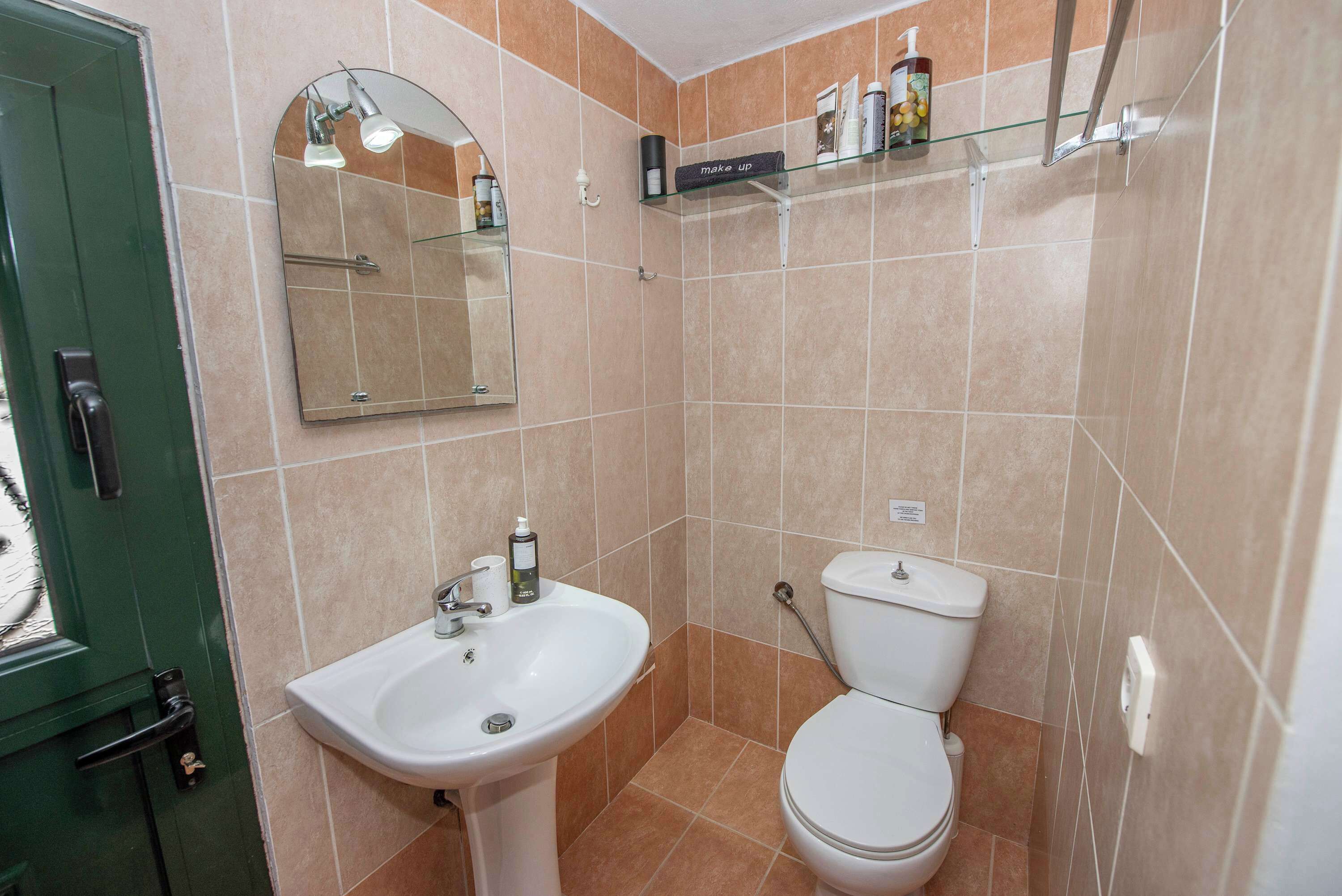 Ein Badezimmer mit Waschbecken, Toilette, Spiegel und Ablagen für Toilettenartikel.