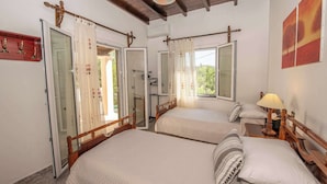 Camera da letto con due letti, una testiera in legno, un comodino con una lampada e una finestra con tende.