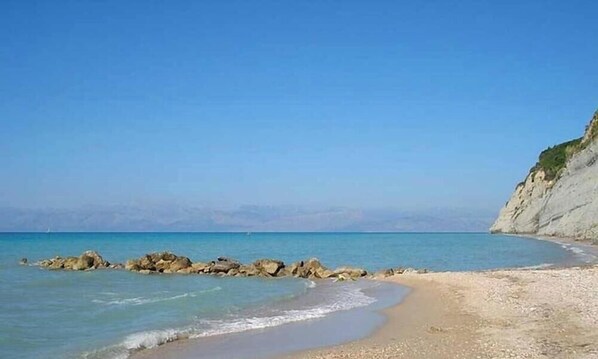 A beach with clear blue water, rocky outcrops, and a sandy shore. - Green Yard Gem - Family Getaway in Sidari, Corfu (Antiperni)