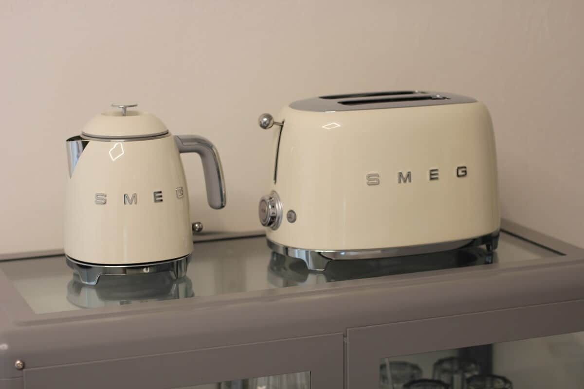 Eine Küche mit einem weißen Smeg-Kaffeekocher und einem Toaster auf einer Glas Arbeitsplatte.