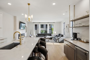 Una cocina moderna con una isla central, electrodomésticos integrados y un comedor con taburetes de bar.