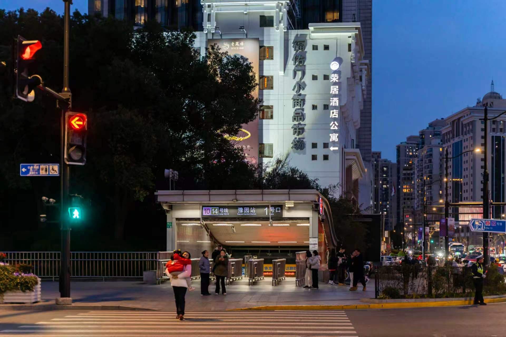 A building with signage indicating a commercial area, a pedestrian crossing, and a bus stop.