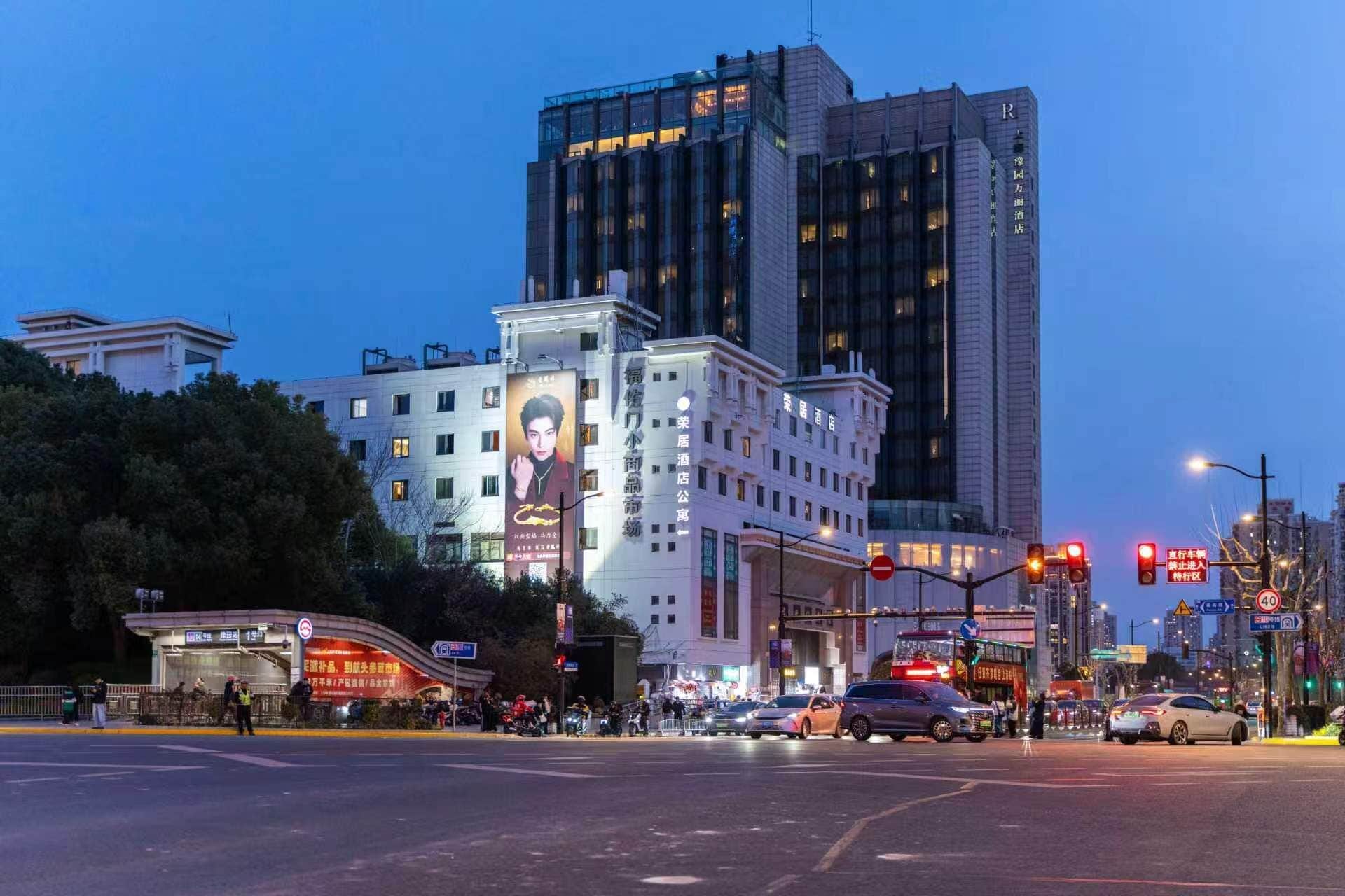 A hotel with a large billboard, a modern building, and a busy intersection.