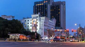 A hotel with a large billboard, a modern building, and a busy intersection.