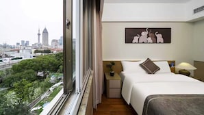 A hotel room with a bed, a nightstand, a lamp, a painting, and a view of a cityscape. - Shanghai Rongju Hotel (Shanghai)