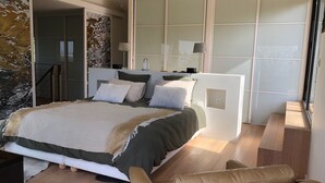 Un dormitorio moderno con una cama grande, un armario empotrado y una zona de estar.