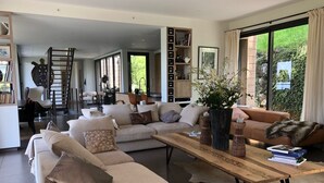 Una sala de estar moderna con un sofá modular, una mesa de centro y vistas a zonas verdes.