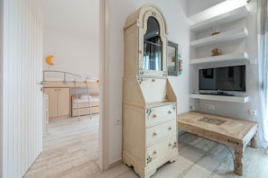 Ein Schlafzimmer mit Etagenbett, Kommode mit Spiegel, Fernseher und Schreibtisch.