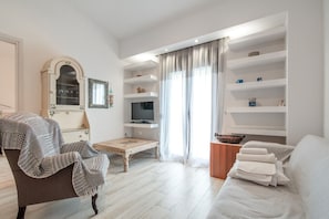 Ein modernes Wohnzimmer mit einer Couch, einem Sessel, einem Fernseher und Einbauschränken.