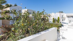 Ein Wohngebiet mit weißen Gebäuden, einem Balkon und blauem Himmel.